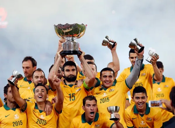 Australia's captain Mile Jedinak holds up the Asian Cup trophy as the team celebrates after winning their Asian Cup final soccer match against South Korea at the Stadium Australia in Sydney