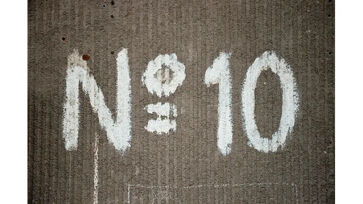 Large number sign with a capital N and the number 10 painted in white on an old building wall with a distinctive texture.