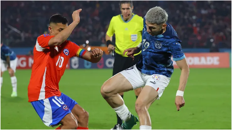 Alexis Sanchez of Chile (L) fights for the ball with Julio Enciso of Paraguay