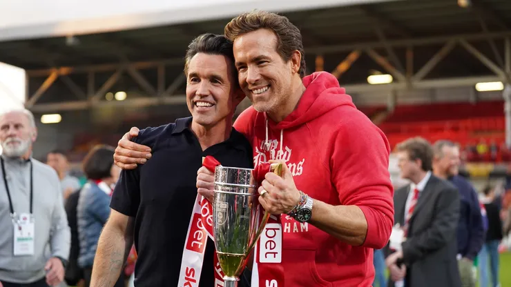 Rob McElhenney and Ryan Reynolds, co-owners of Wrexham AFC, pose for a photo with the trophy following the club's promotion to the Sky Bet Championship during the Sky Bet League One match between Wrexham AFC and Charlton Athletic FC at Racecourse Ground on April 26, 2025 in Wrexham, Wales.