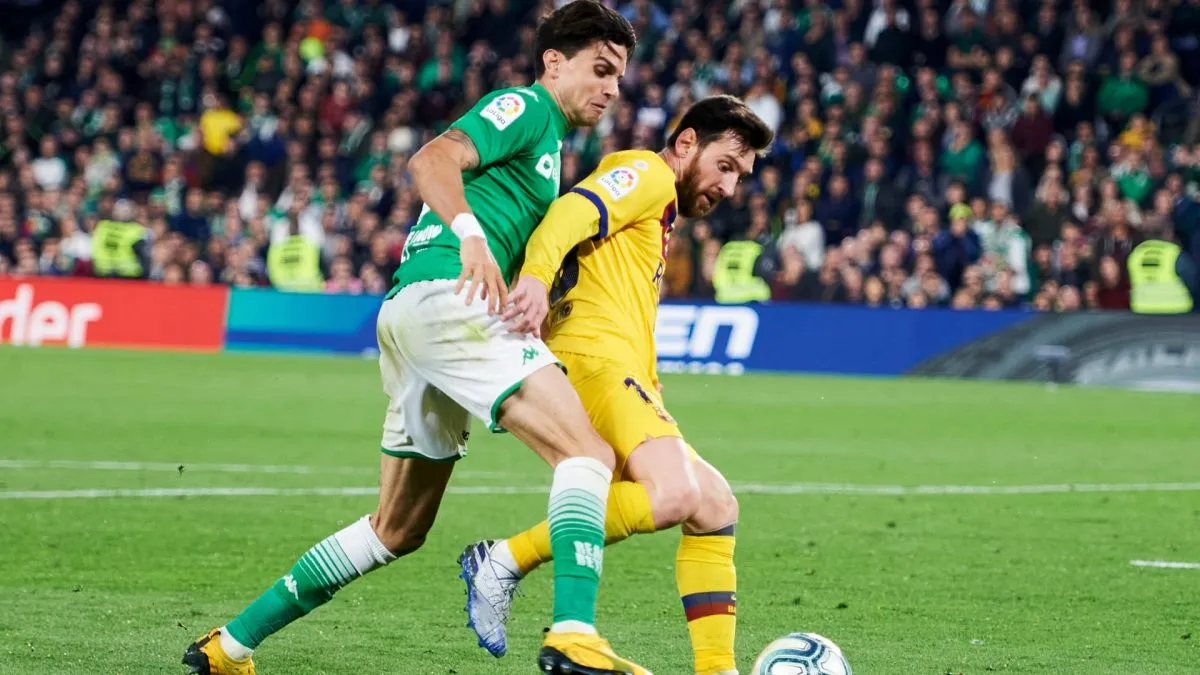Lionel Messi duels for the ball with Marc Bartra during a La Liga match between Real Betis and Barcelona on February 09, 2020.