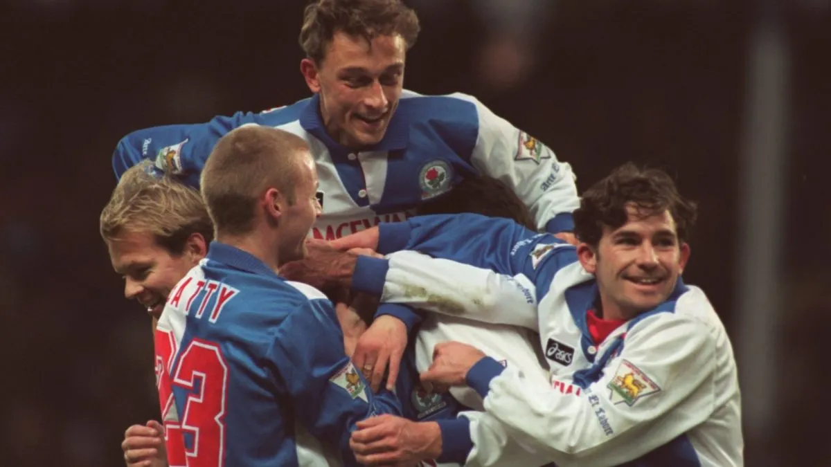 Alan Shearer if Engulfed by Blackburn Rovers players celebreatting his 100 goal for the club during the Premier League match in 1995. (Source: Mike Cooper/ALLSPORT)