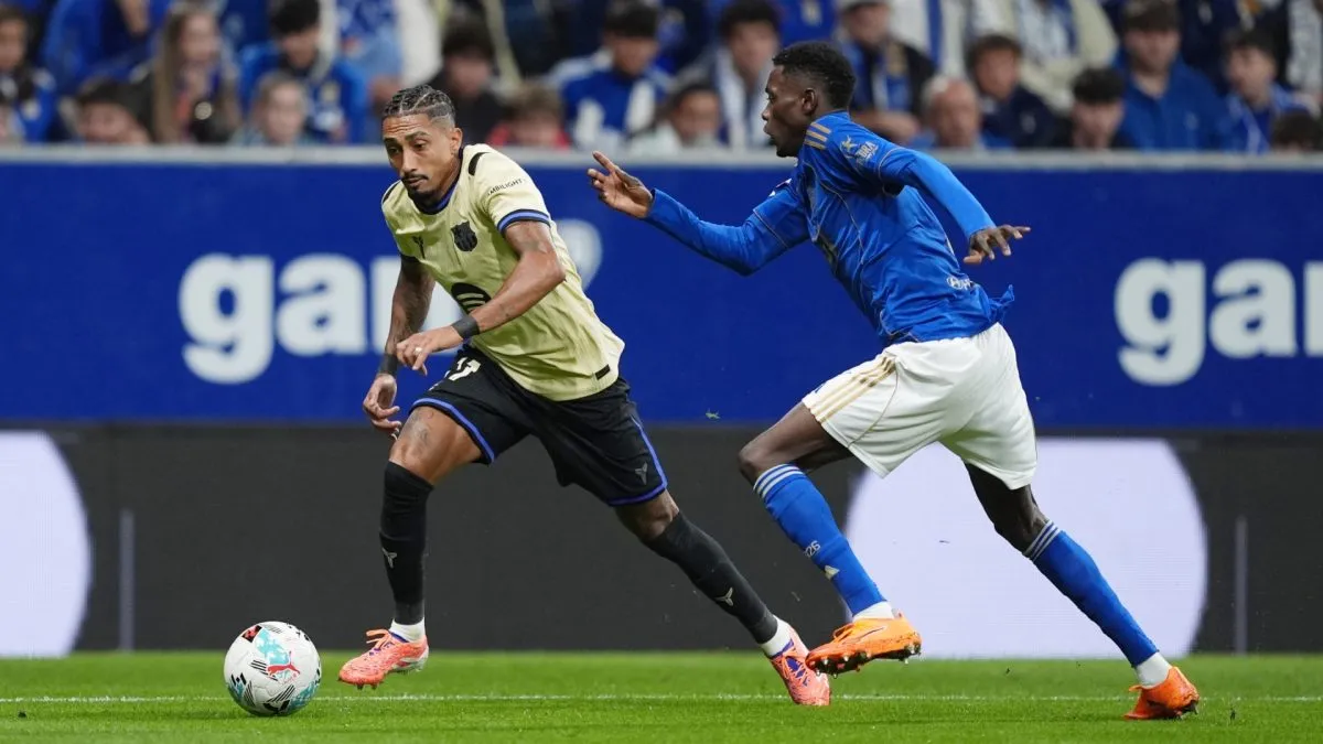 Raphinha of FC Barcelona runs with the ball as he is closed down by Rahim Alhassane of Real Oviedo.