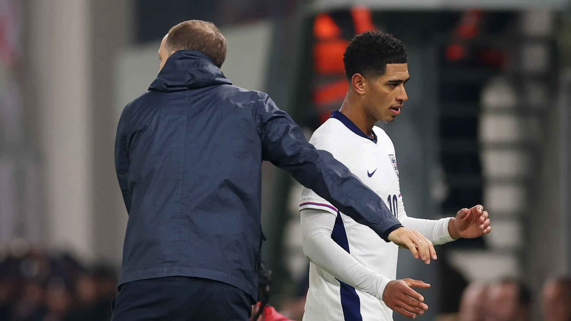 Jude Bellingham of England walks past Thomas Tuchel, Head Coach of England, after being substituted.