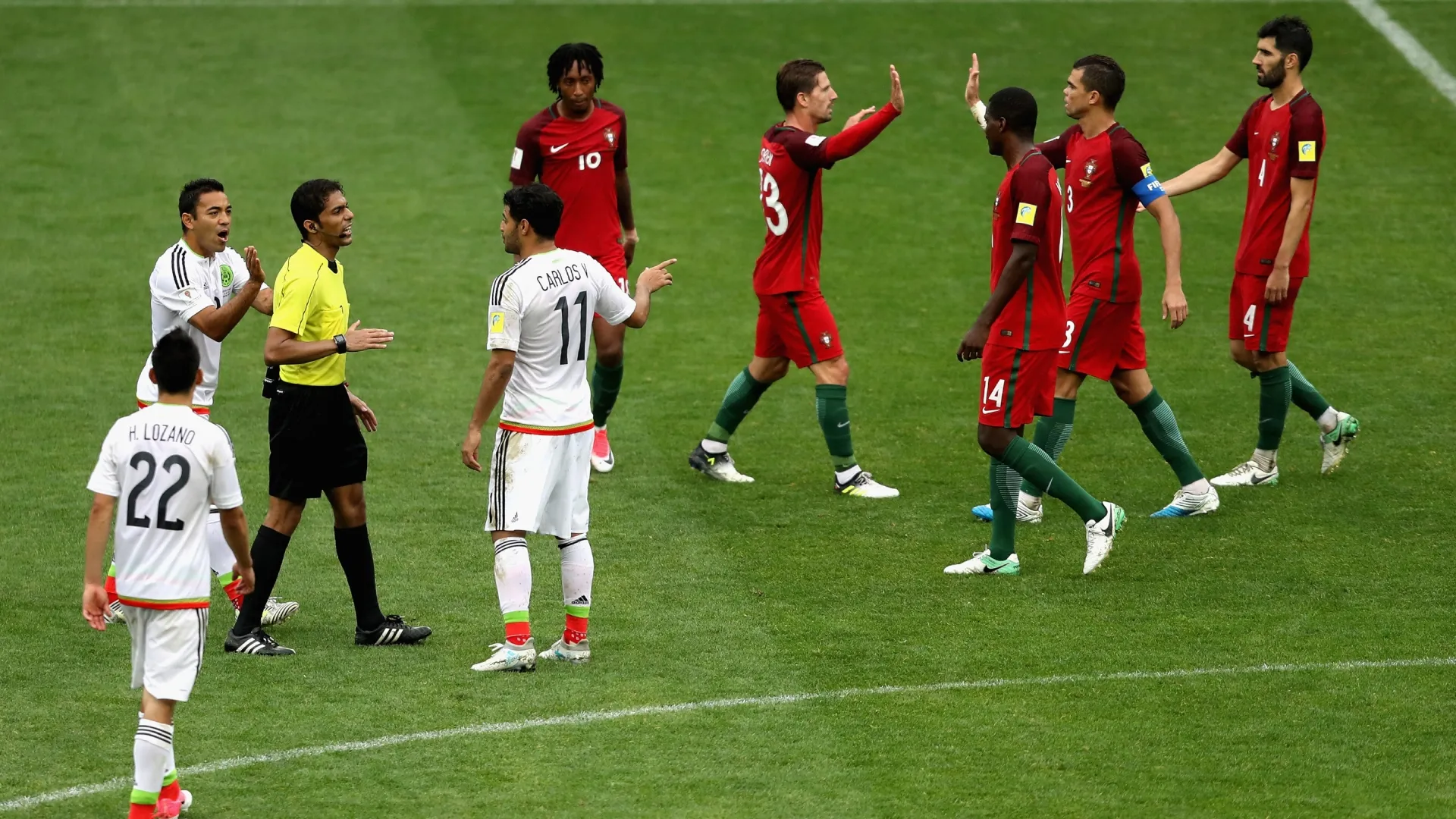 Portugal players celebrate winning as the Mexico players confront Referee Fahad Al Mirdasi after the FIFA Confederations Cup.