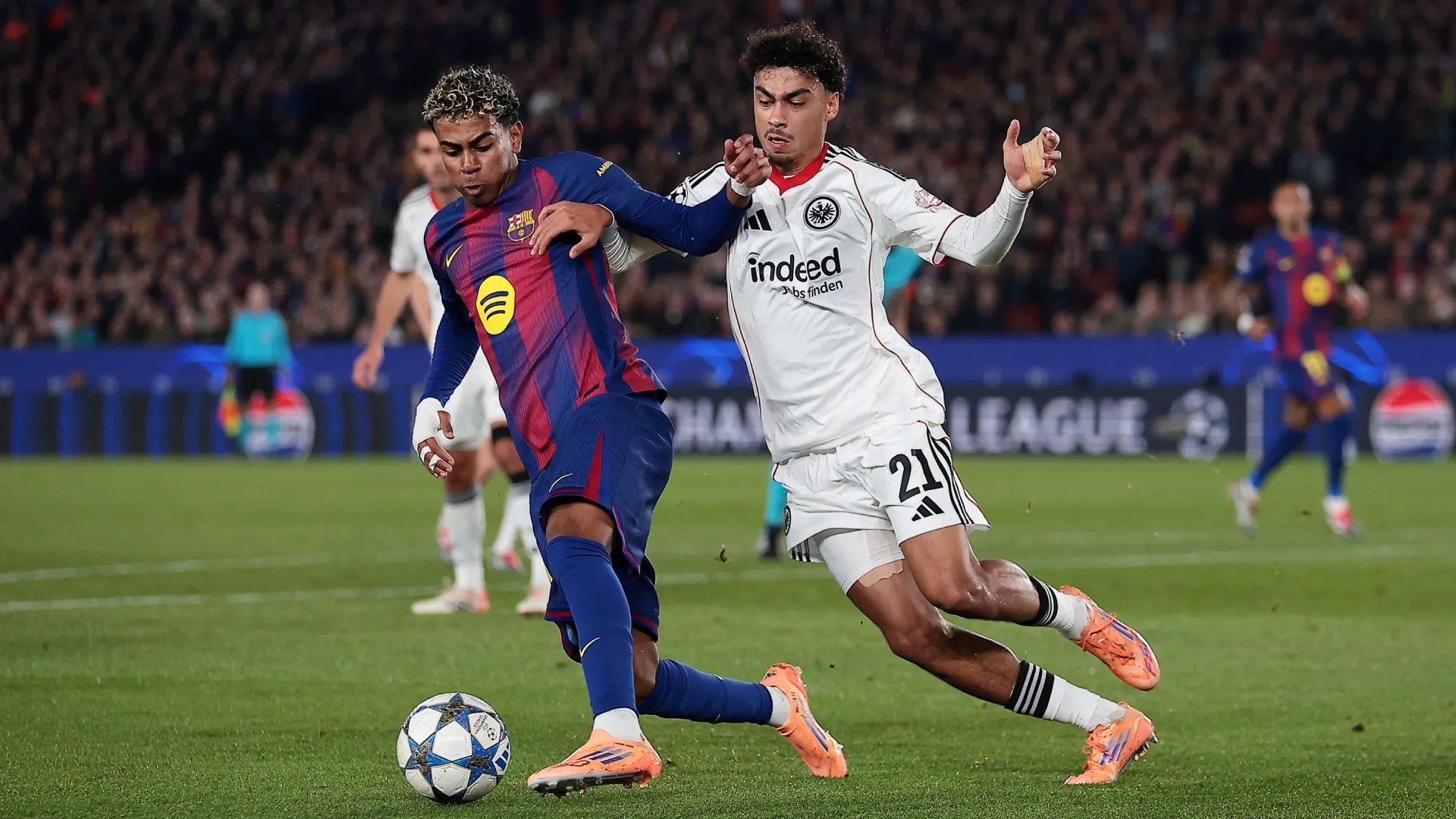 Lamine Yamal of FC Barcelona is challenged by Nathaniel Brown of Eintracht Frankfurt.