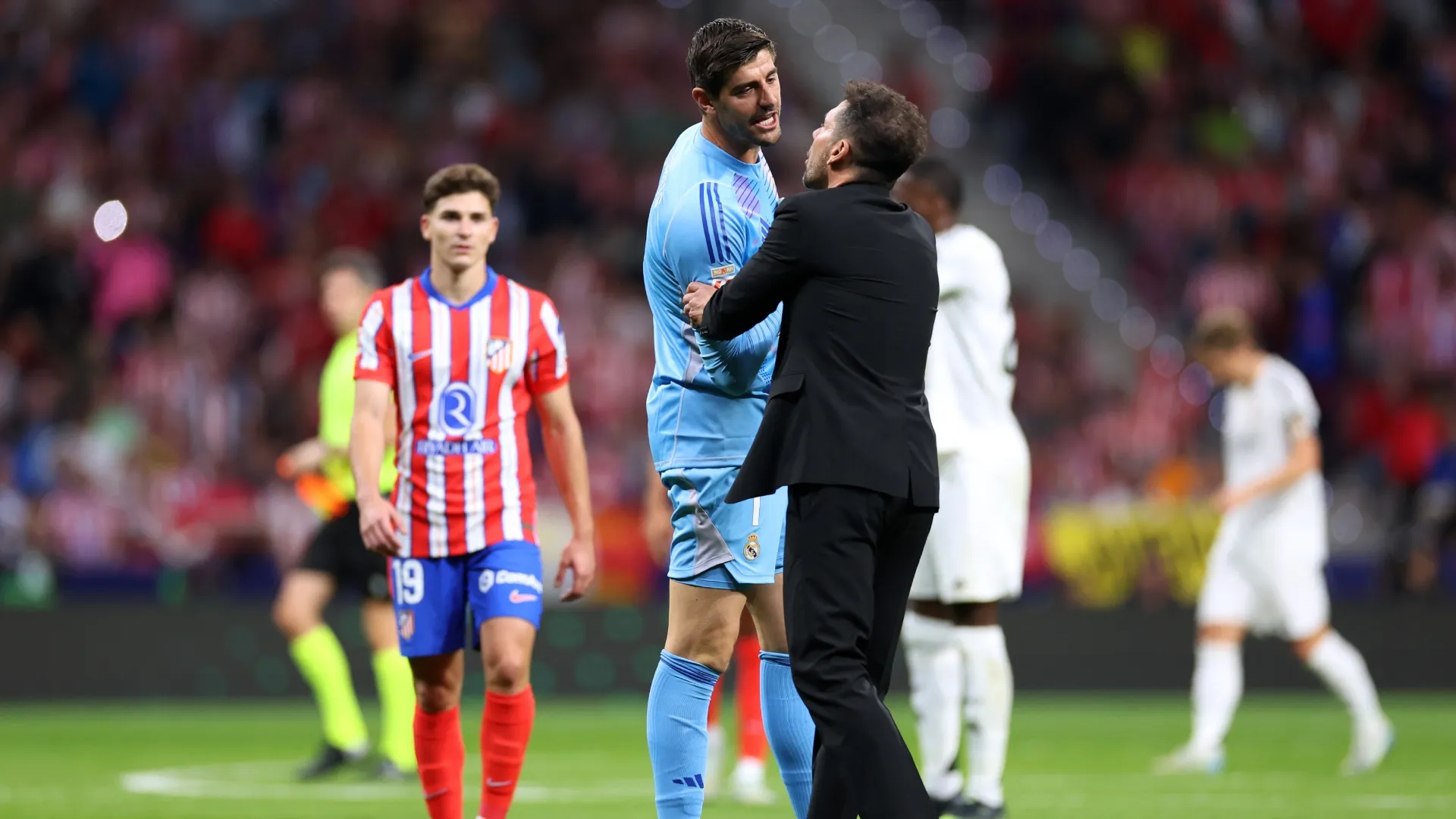 Thibaut Courtois of Real Madrid interacts with Diego Simeone, head coach of Atletico de Madrid, in 2024.