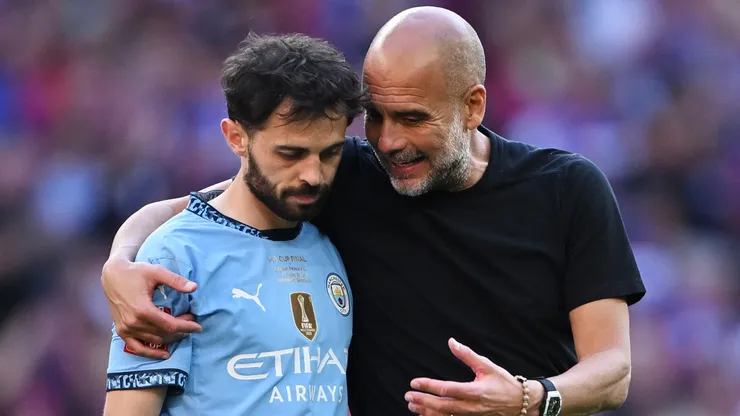 Pep Guardiola, Manager of Manchester City, interacts with Bernardo Silva.
