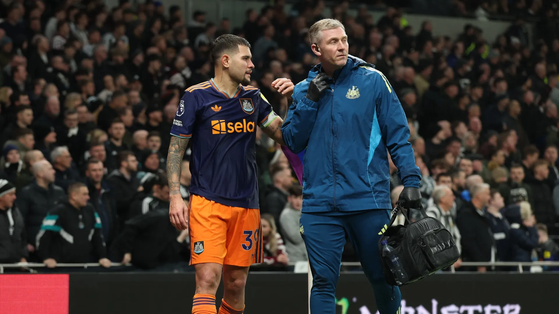 Bruno Guimaraes of Newcastle United walks off the pitch with a medical staff member.