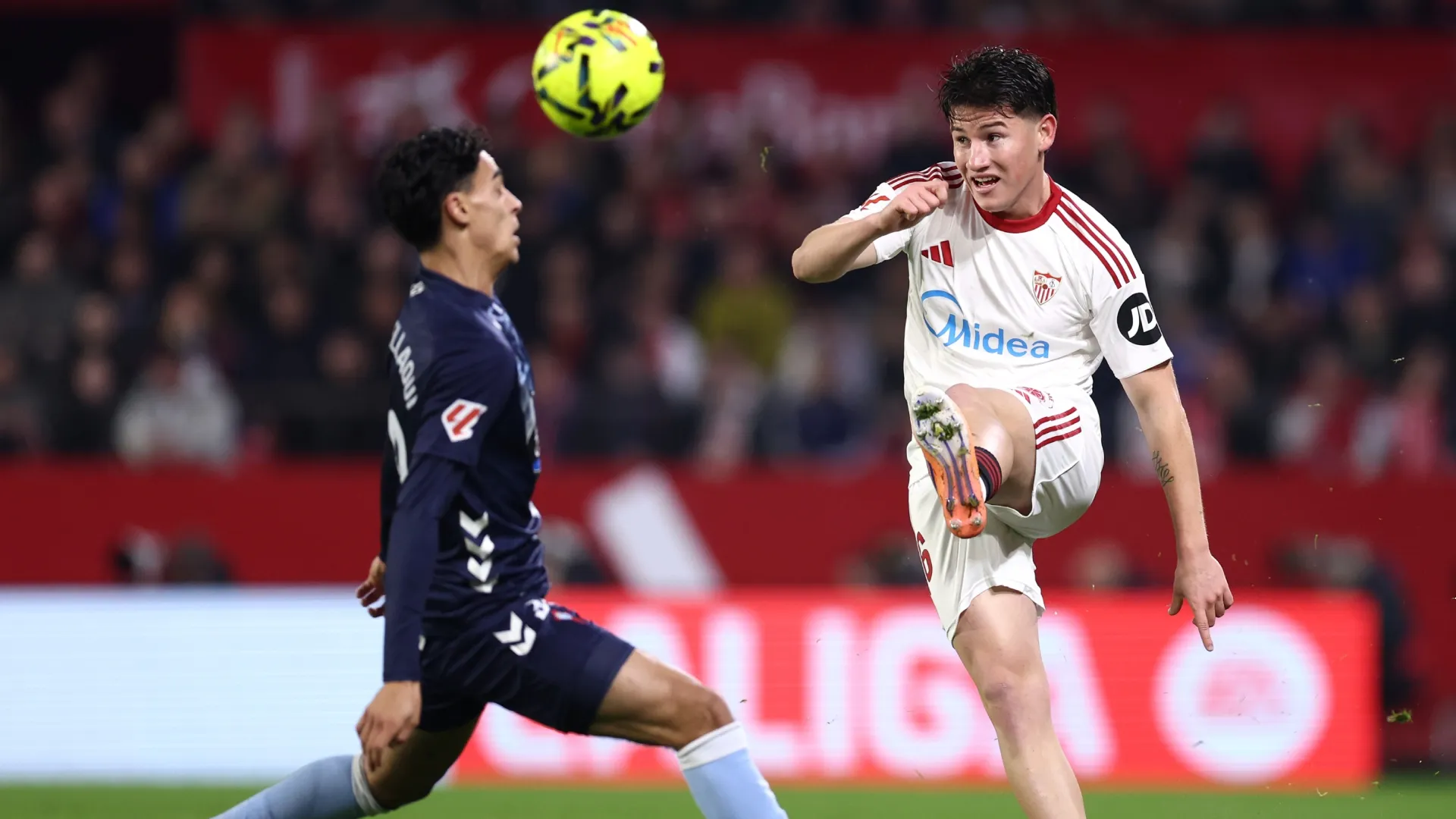 Oso of Sevilla FC crosses the ball whilst under pressure from Miguel Roman of Celta Vigo.