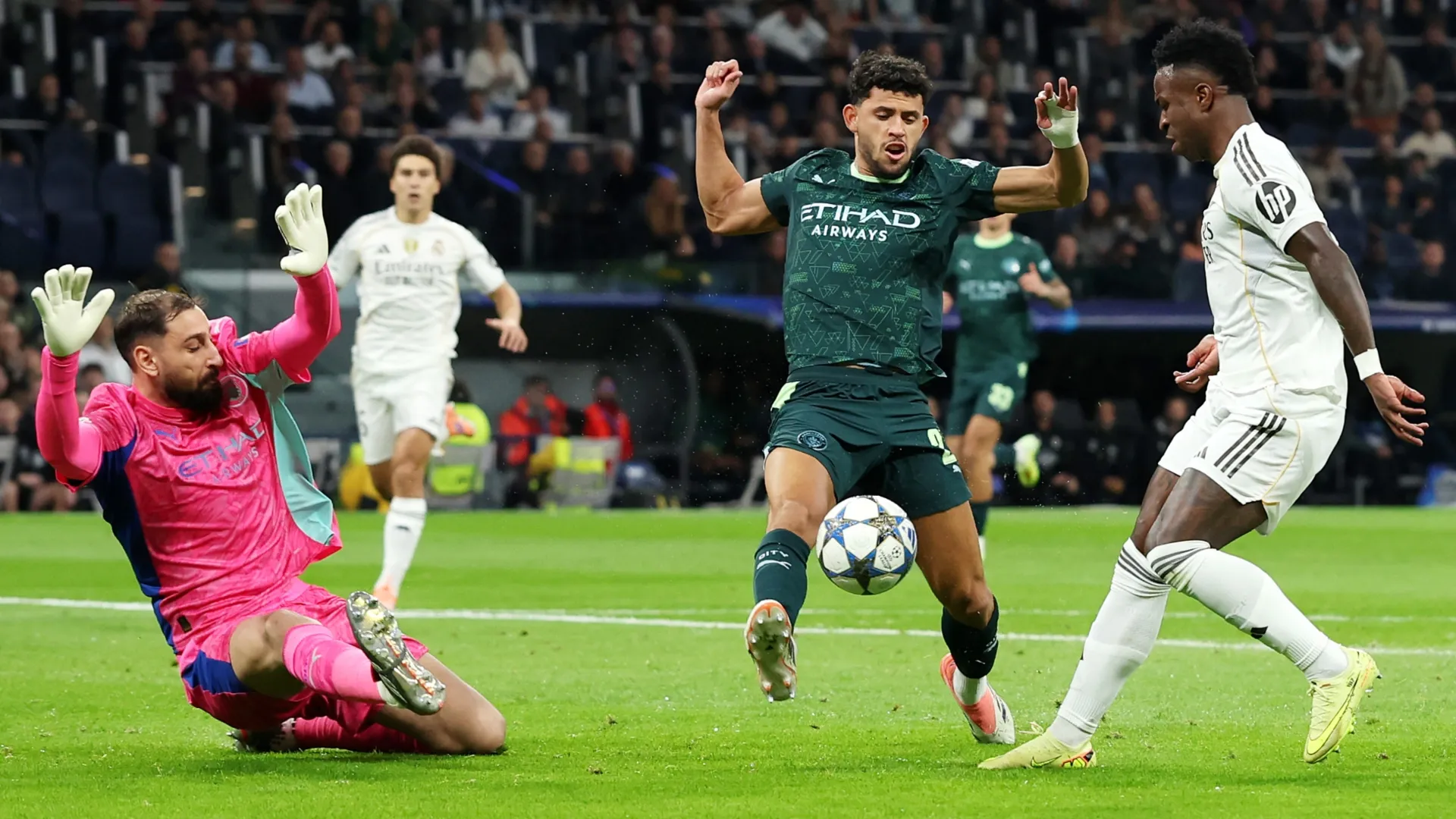 Vinicius Junior of Real Madrid misses a chance as he is challenged by Matheus Nunes and Gianluigi Donnarumma of Manchester City.