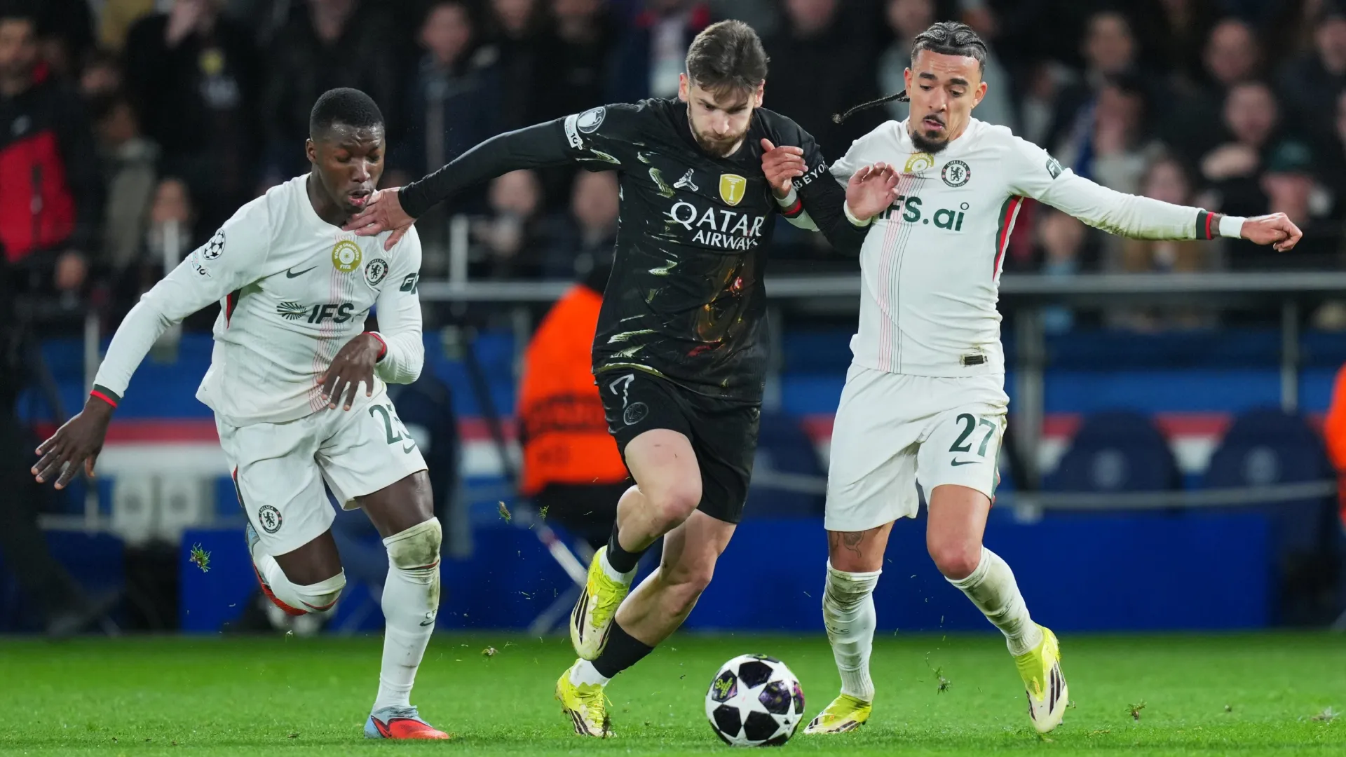 Khvicha Kvaratskhelia of Paris Saint-Germain runs with the ball whilst under pressure from Moises Caicedo and Malo Gusto of Chelsea.