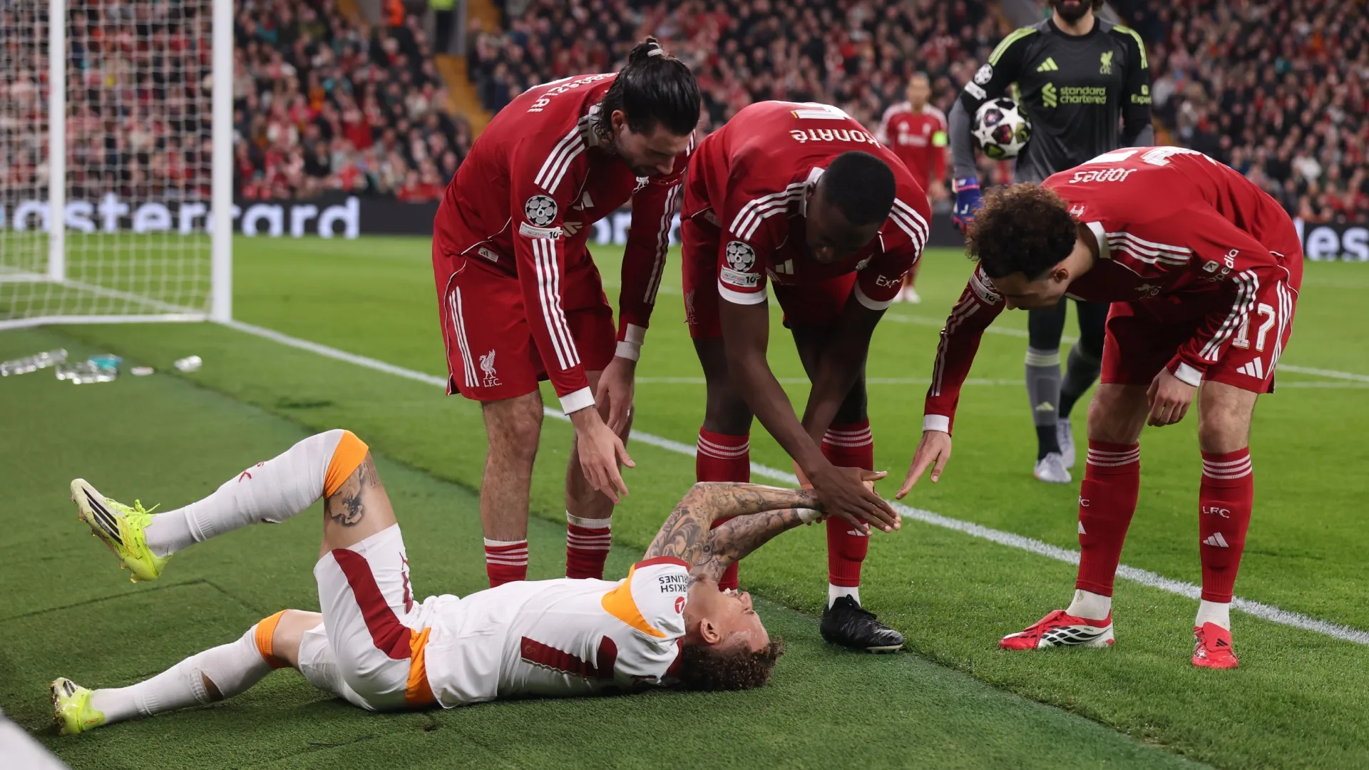 Noa Lang of Galatasaray A.S. reacts to a thumb injury as Liverpool players surround him.