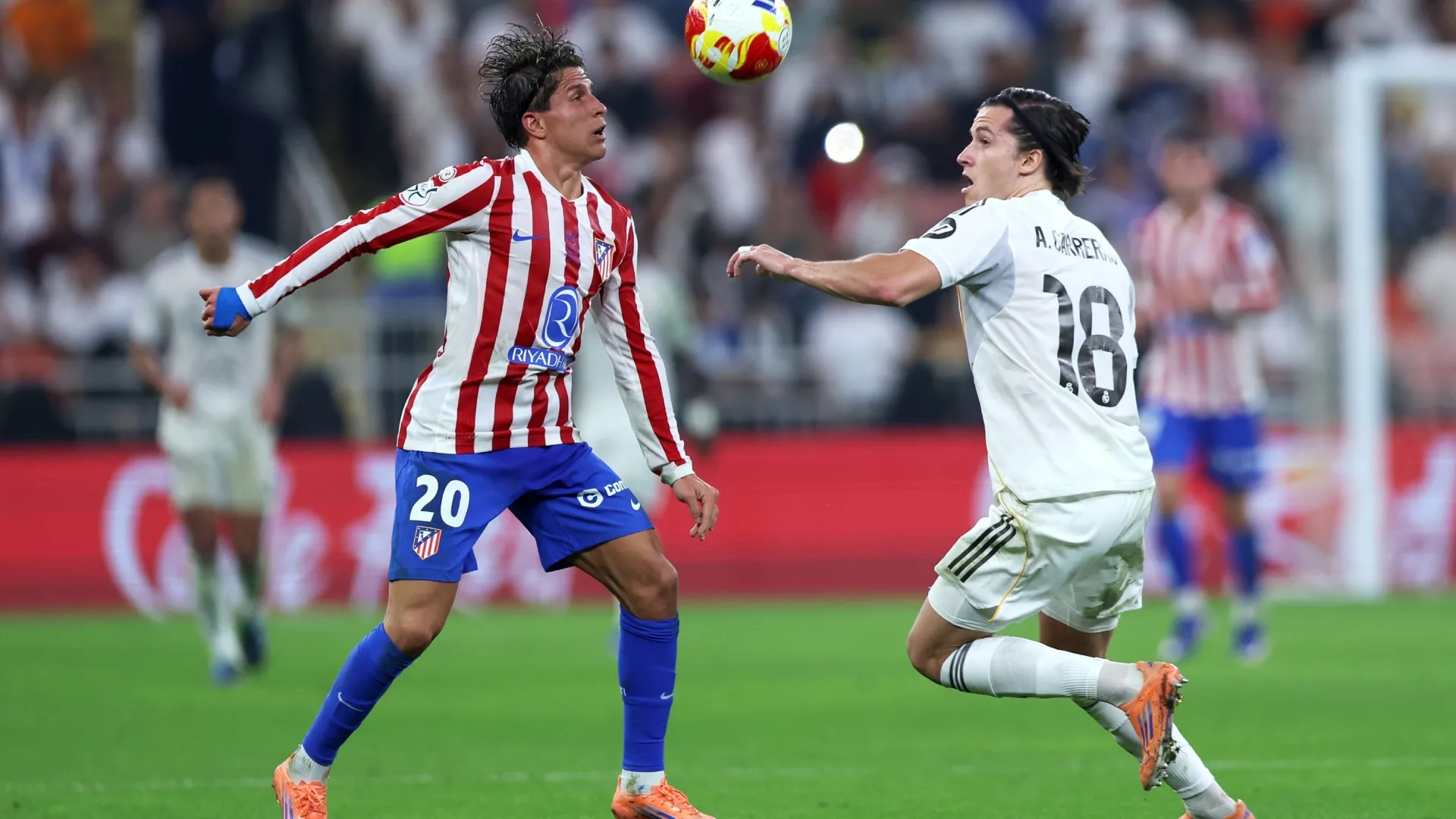 Alvaro Carreras of Real Madrid battles for possession with Giuliano Simeone of Atletico de Madrid.