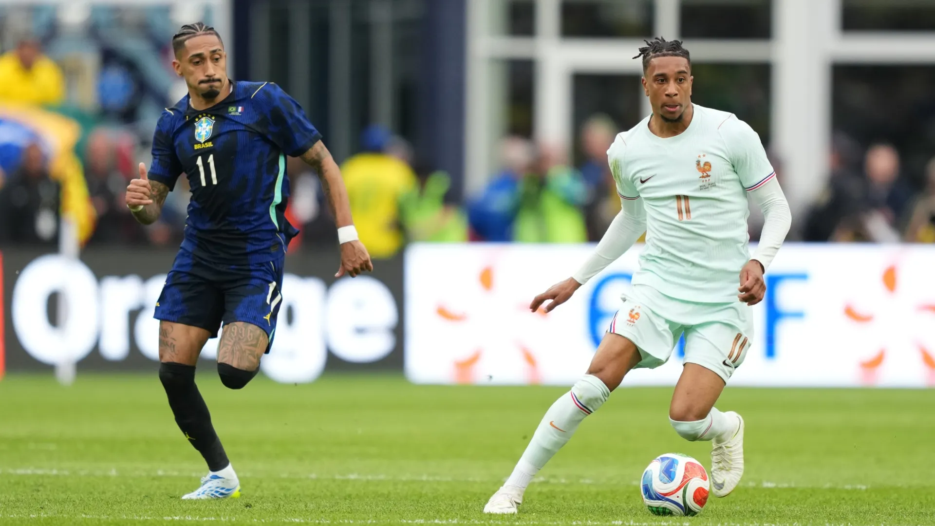 Michael Olise of France runs with the ball against Raphinha of Brazil.