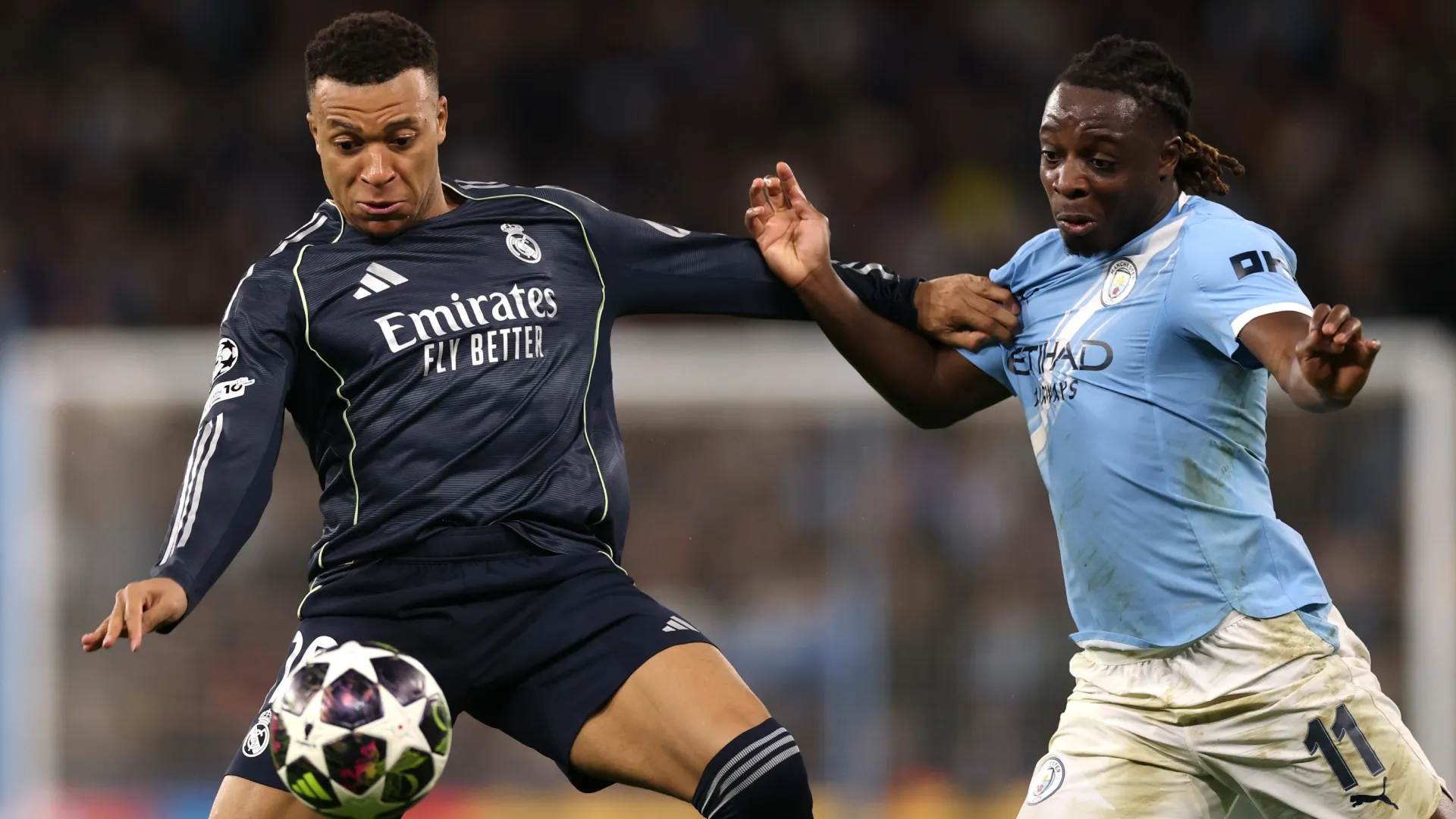 Kylian Mbappe of Real Madrid battles for possession with Jeremy Doku of Manchester City.