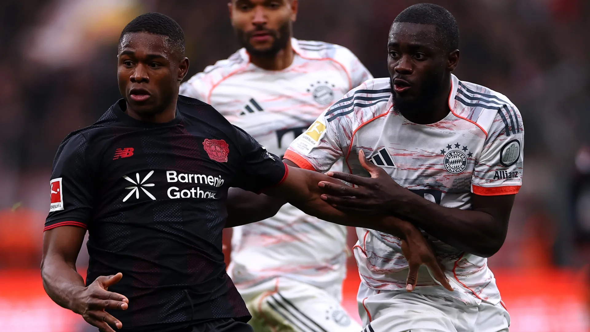 Christian Kofane of Bayer Leverkusen battles for the ball with Dayot Upamecano of Bayern Munich.