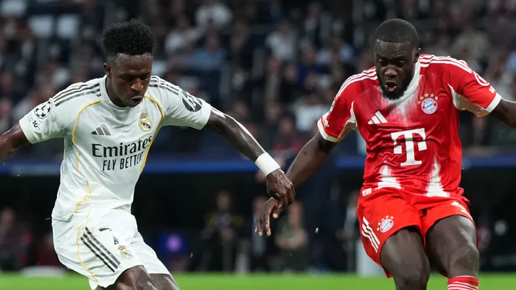 Vinicius Junior of Real Madrid shoots while under pressure from Dayot Upamecano of Bayern Munich