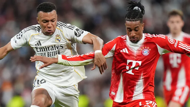 Michael Olise of FC Bayern Munich is challenged by Kylian Mbappe of Real Madrid.