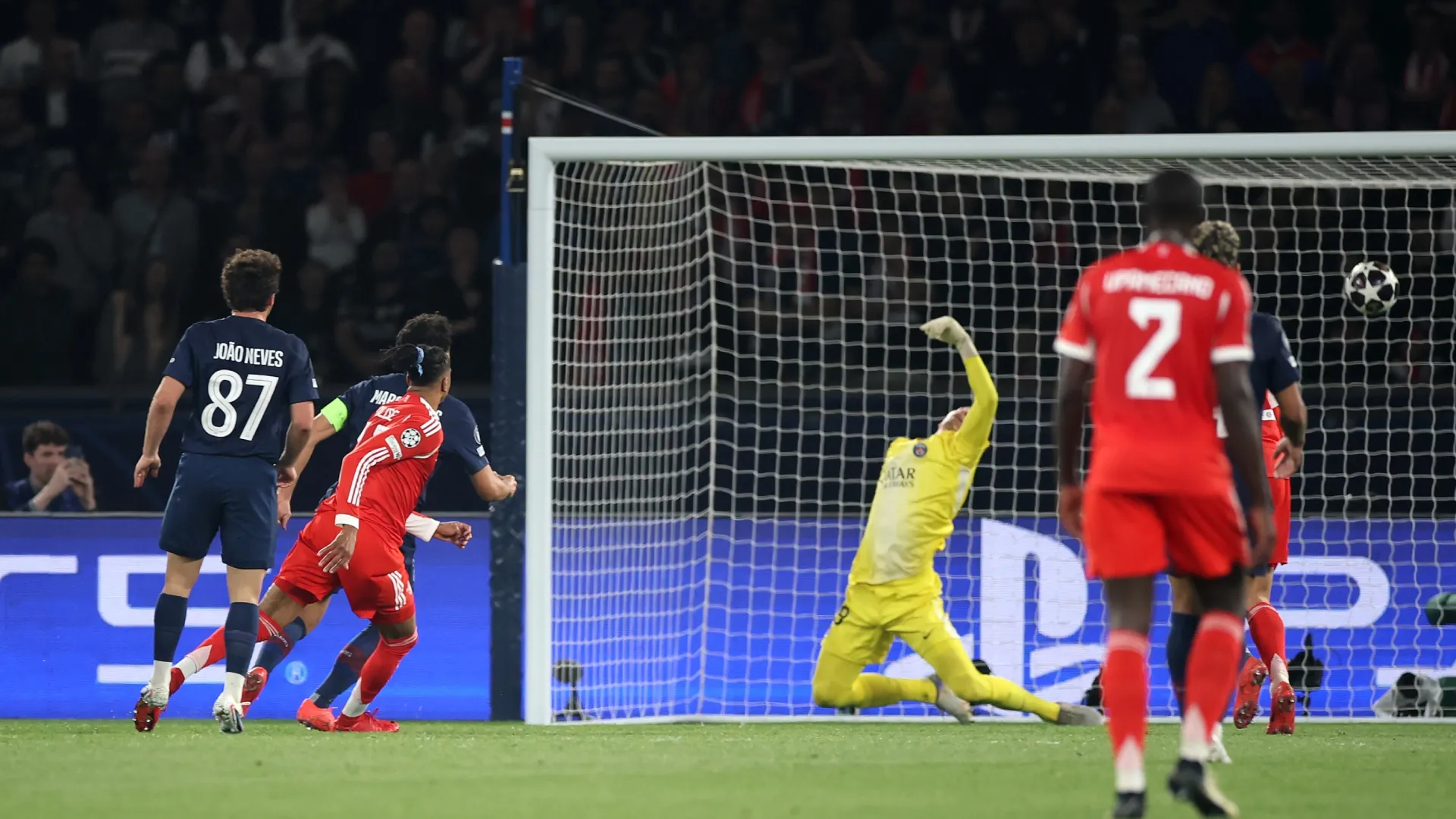 Michael Olise of FC Bayern Munich scores his team's second goal past Matvey Safonov of Paris Saint-Germain.
