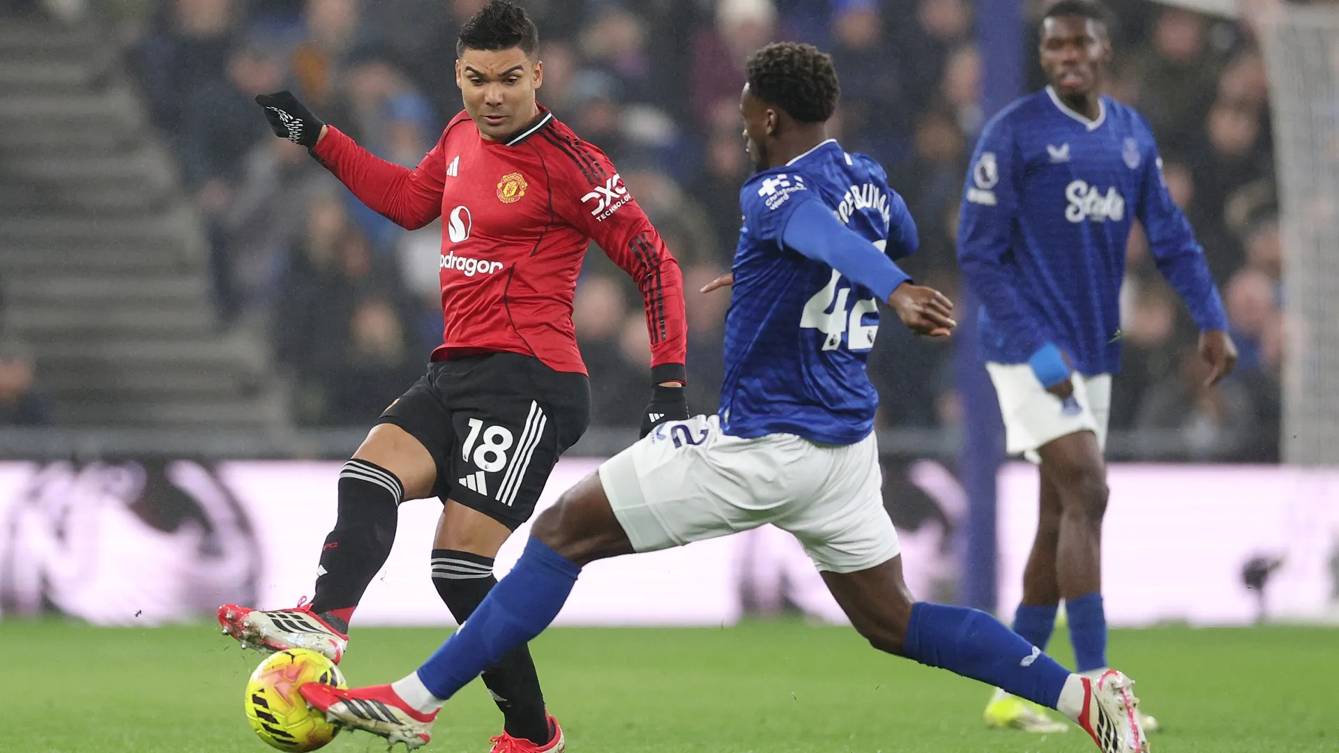 Casemiro of Manchester United passes the ball under pressure from Tim Iroegbunam of Everton.