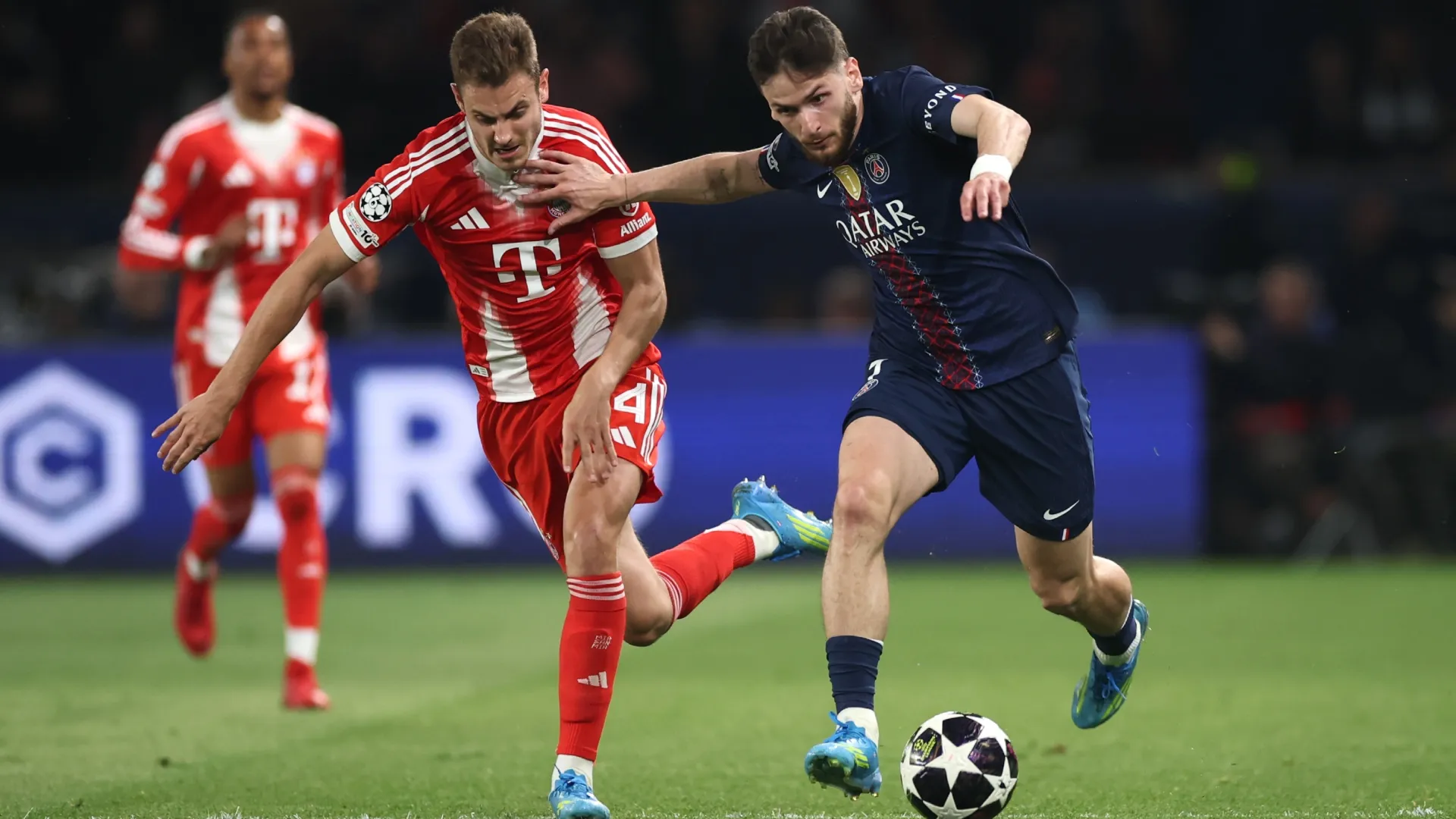 Aleksandar Pavlovic of Bayern Munich is challenged by Khvicha Kvaratskhelia of PSG.
