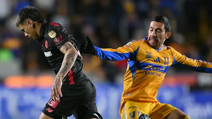 Nicolás Castro of Toluca dribbles past Juan Vigón of Tigres