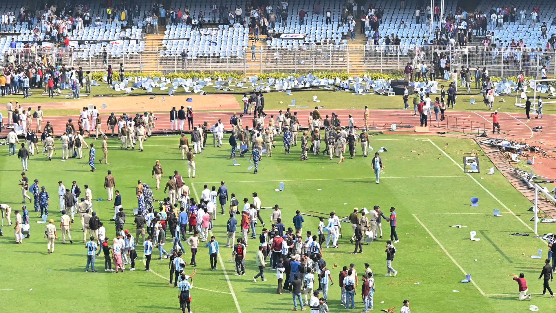 Fans throw chairs and storm on to the field during Messi’s visit. (Getty Images)