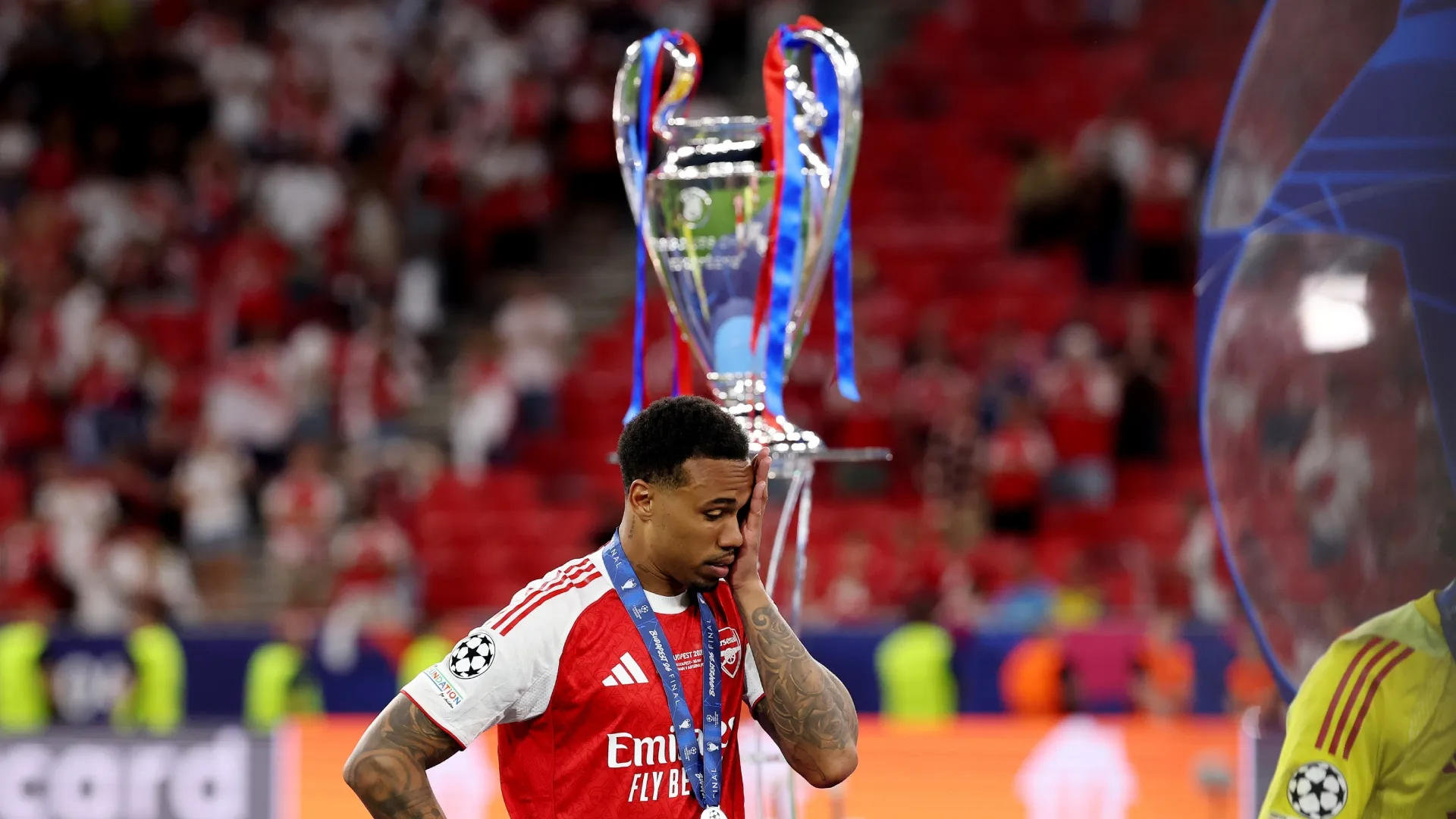 Gabriel of Arsenal looks dejected as he walks past the UEFA Champions League trophy.