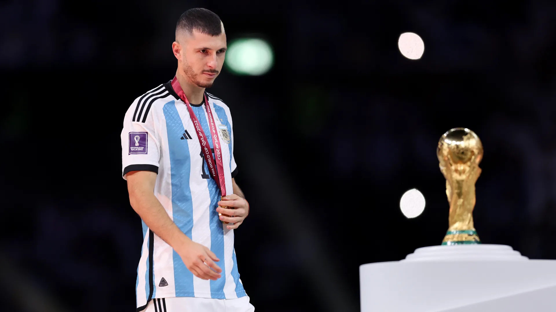 Guido Rodriguez of Argentina looks at the FIFA World Cup Qatar 2022 Winner’s Trophy. (Getty Images)