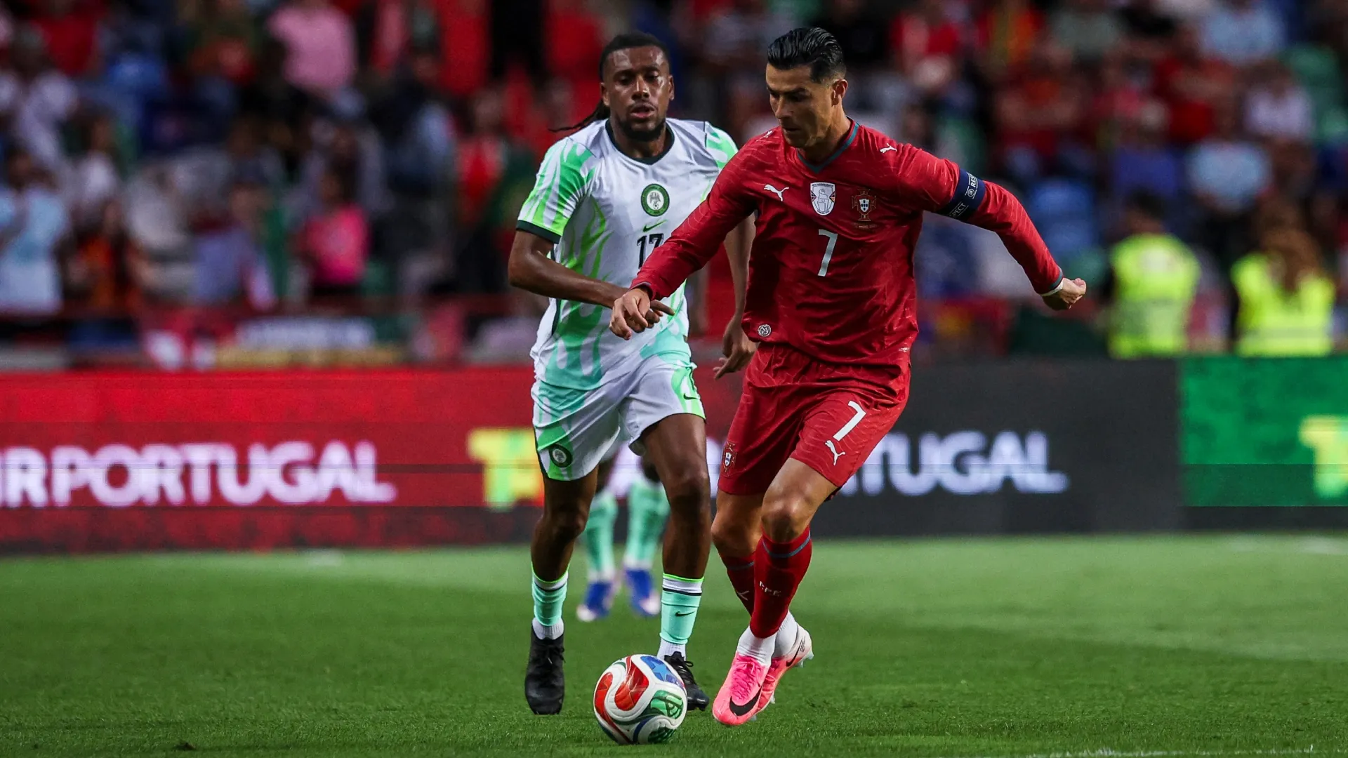 Cristiano Ronaldo of Portugal (R) tries to escape Alex Iwobi of Nigeria (L).