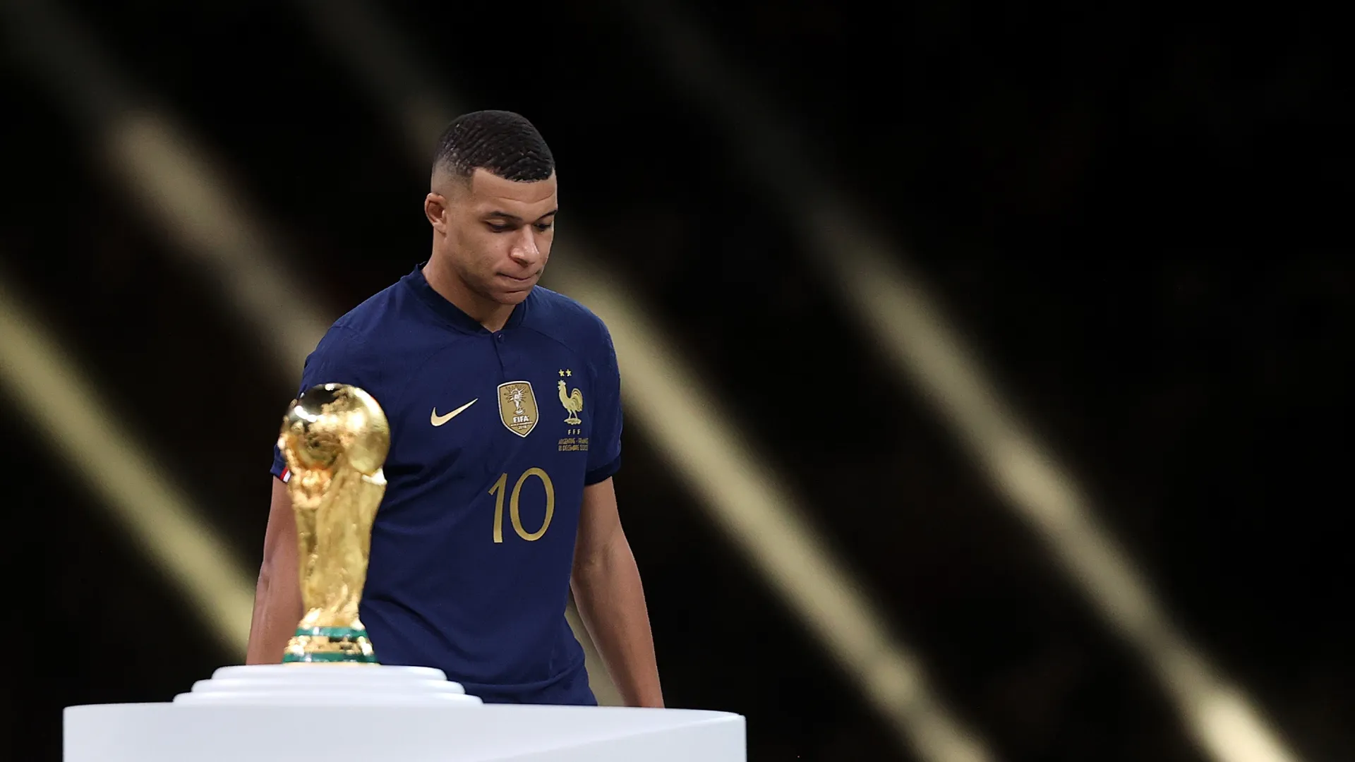 Kylian Mbappe of France walks past the FIFA World Cup trophy in 2022.