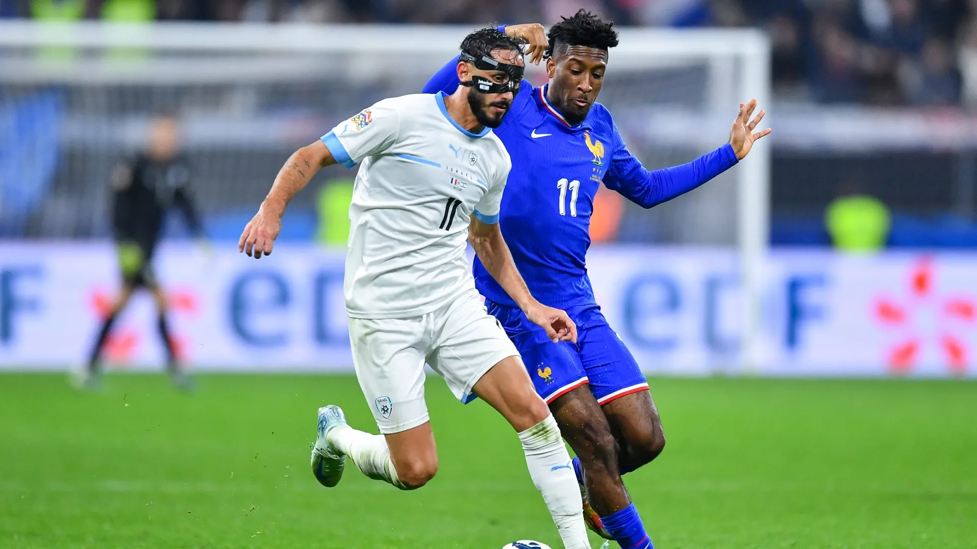 Sagiv Yehezkel of Israel runs with the ball under pressure from Kingsley Coman of France.