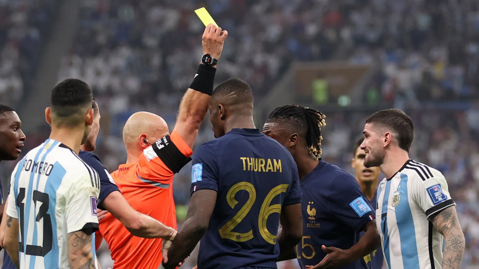 Marcus Thuram of France is shown a yellow card by referee Szymon Marciniak.