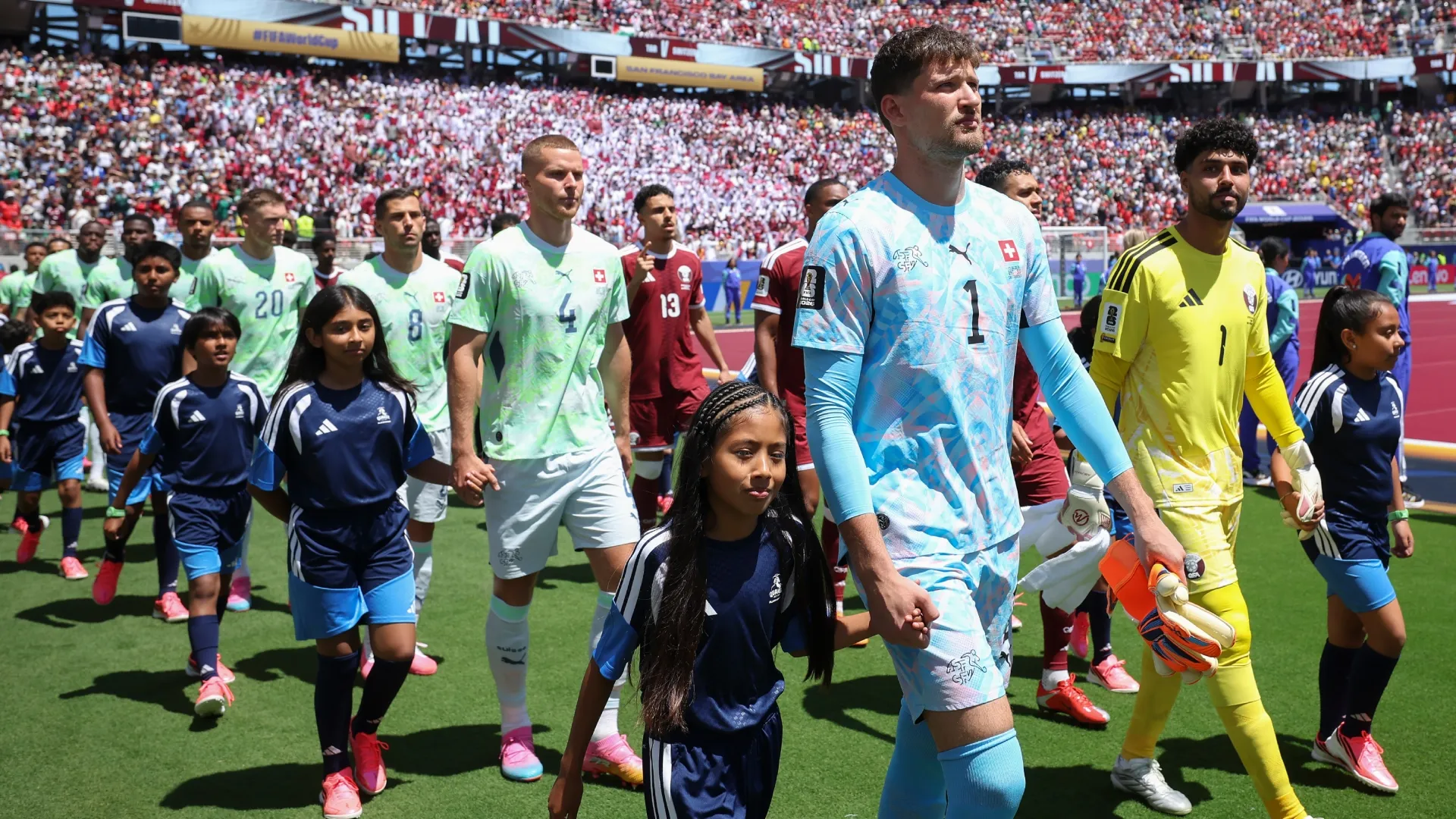 Gregor Kobel #1 of Switzerland and Mahmoud Abunada #1 of Qatar walk onto the field.