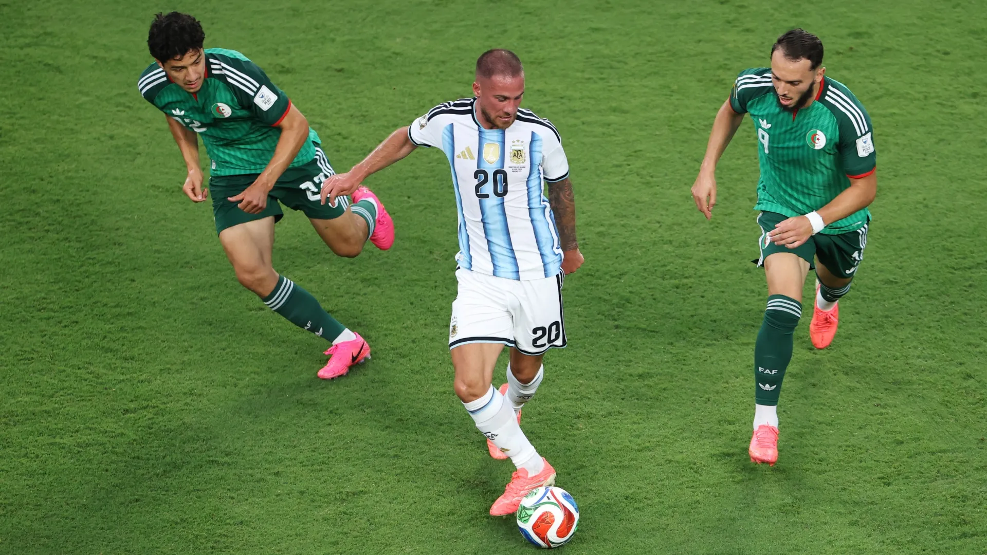 Alexis Mac Allister #20 of Argentina being pressed by Ibrahim Maza #22 and Amine Gouiri #9 of Algeria.