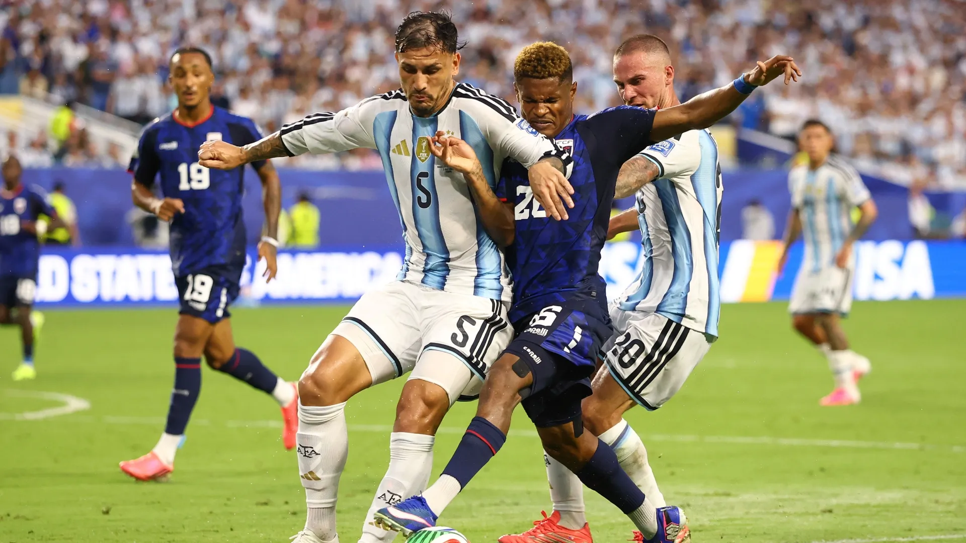 Helio Varela #26 of Cabo Verde competes for the ball against Leandro Paredes #5 and Alexis Mac Allister #20 of Argentina.