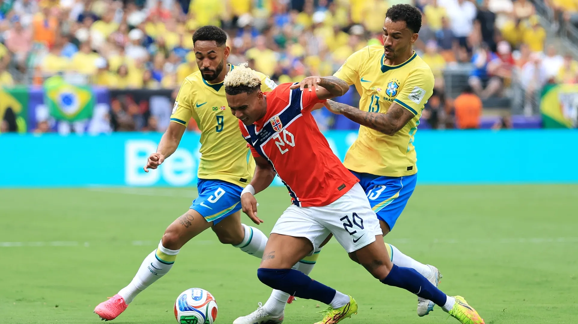 Antonio Nusa #20 of Norway competes for the ball against Matheus Cunha #9 and Danilo #13 of Brazil.