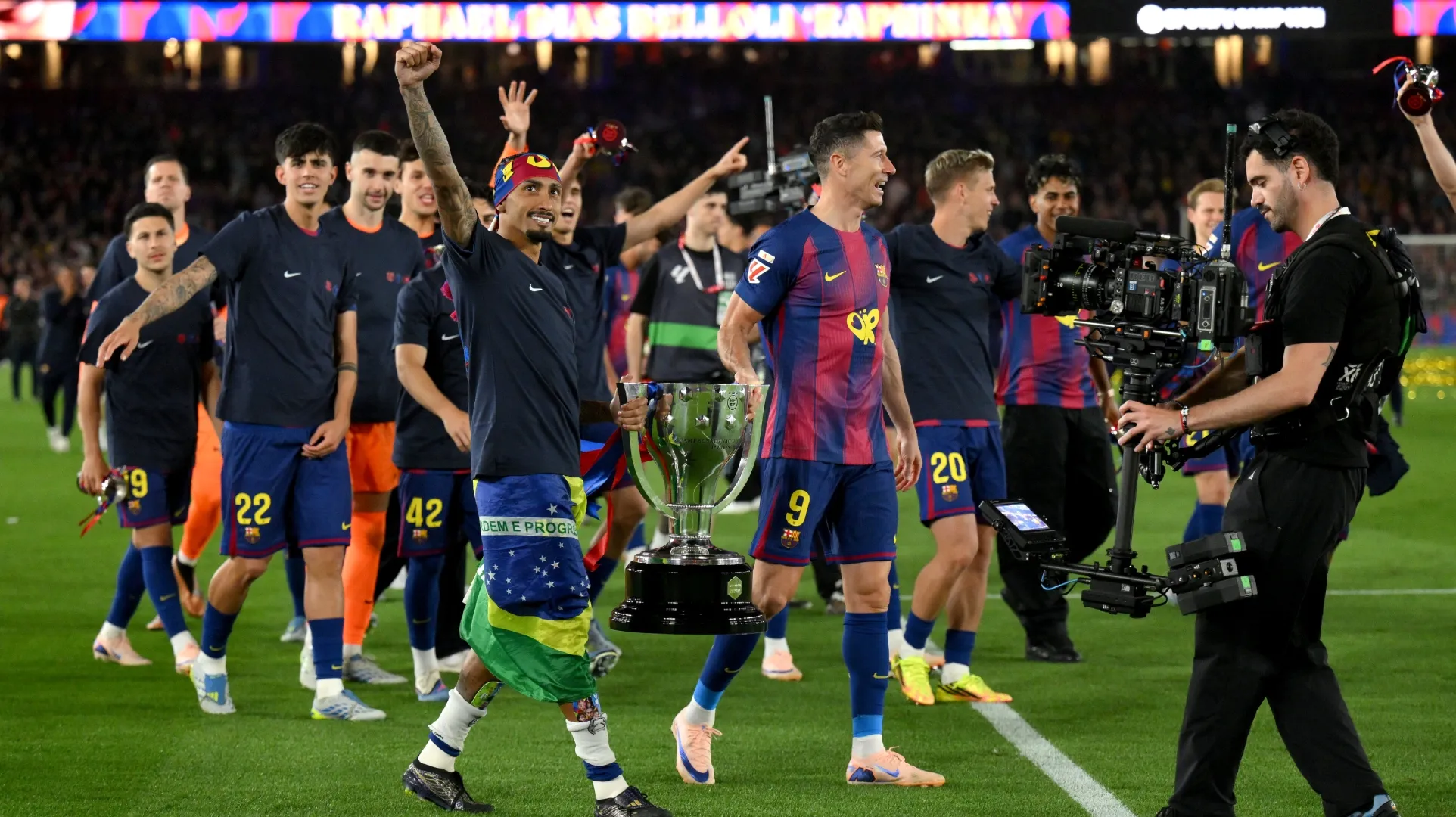 Raphinha and Robert Lewandowski of FC Barcelona carry the 2025-26 La Liga trophy.