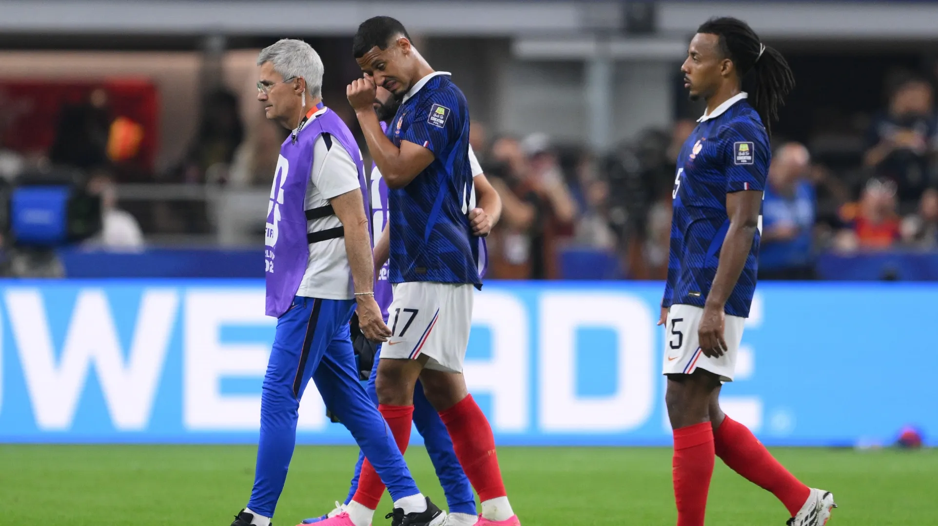 William Saliba #17 of France walks off the pitch with medical staff after sustaining an injury.