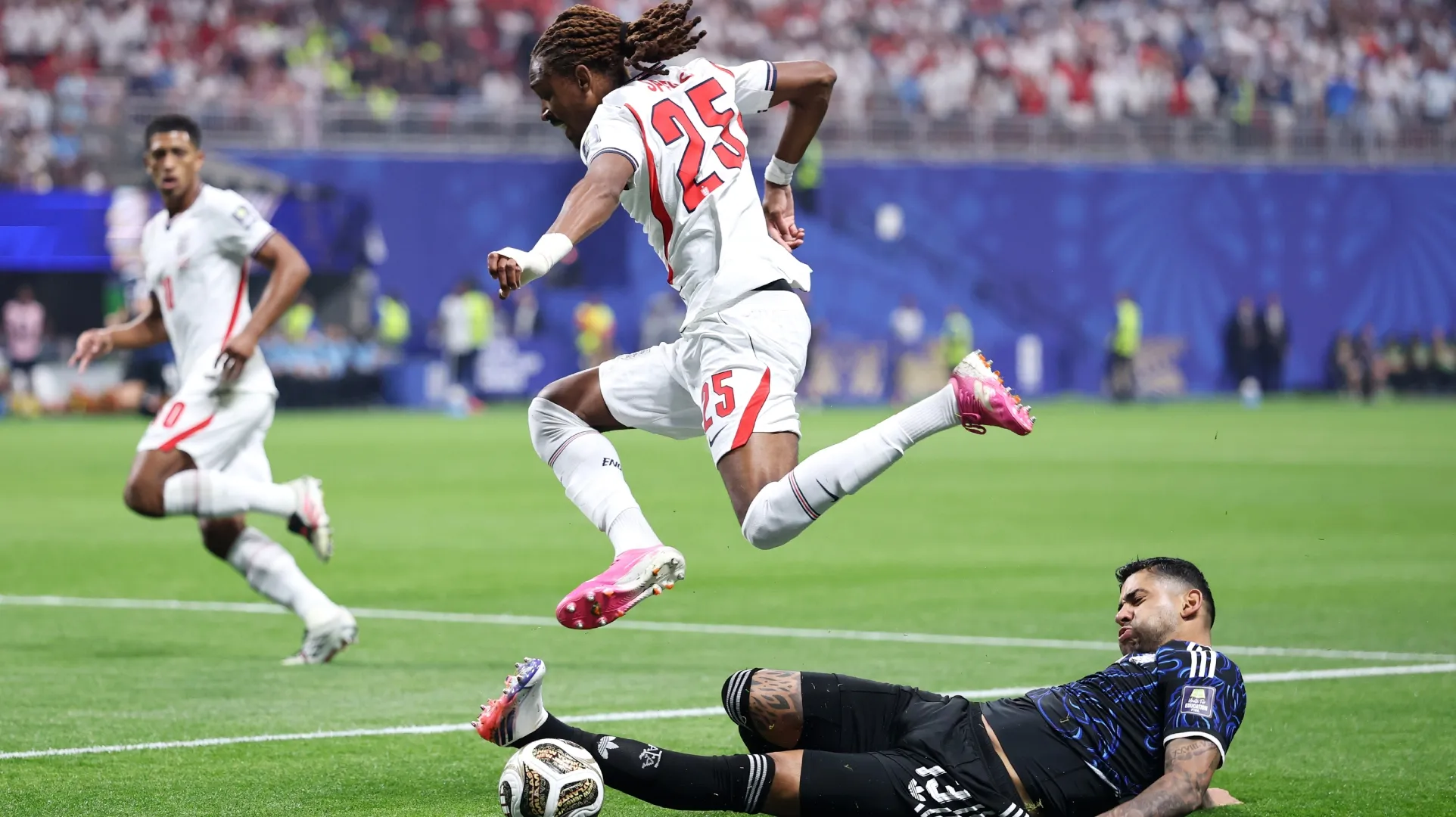 Djed Spence #25 of England is tackled by Cristian Romero #13 of Argentina.