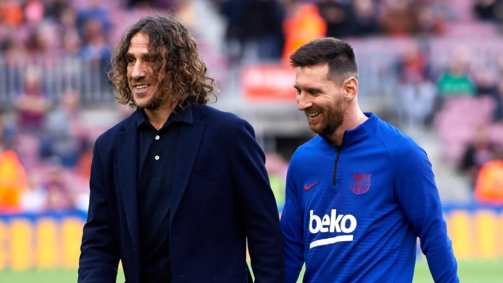 Lionel Messi of FC Barcelona walks with former teammate Carles Puyol.