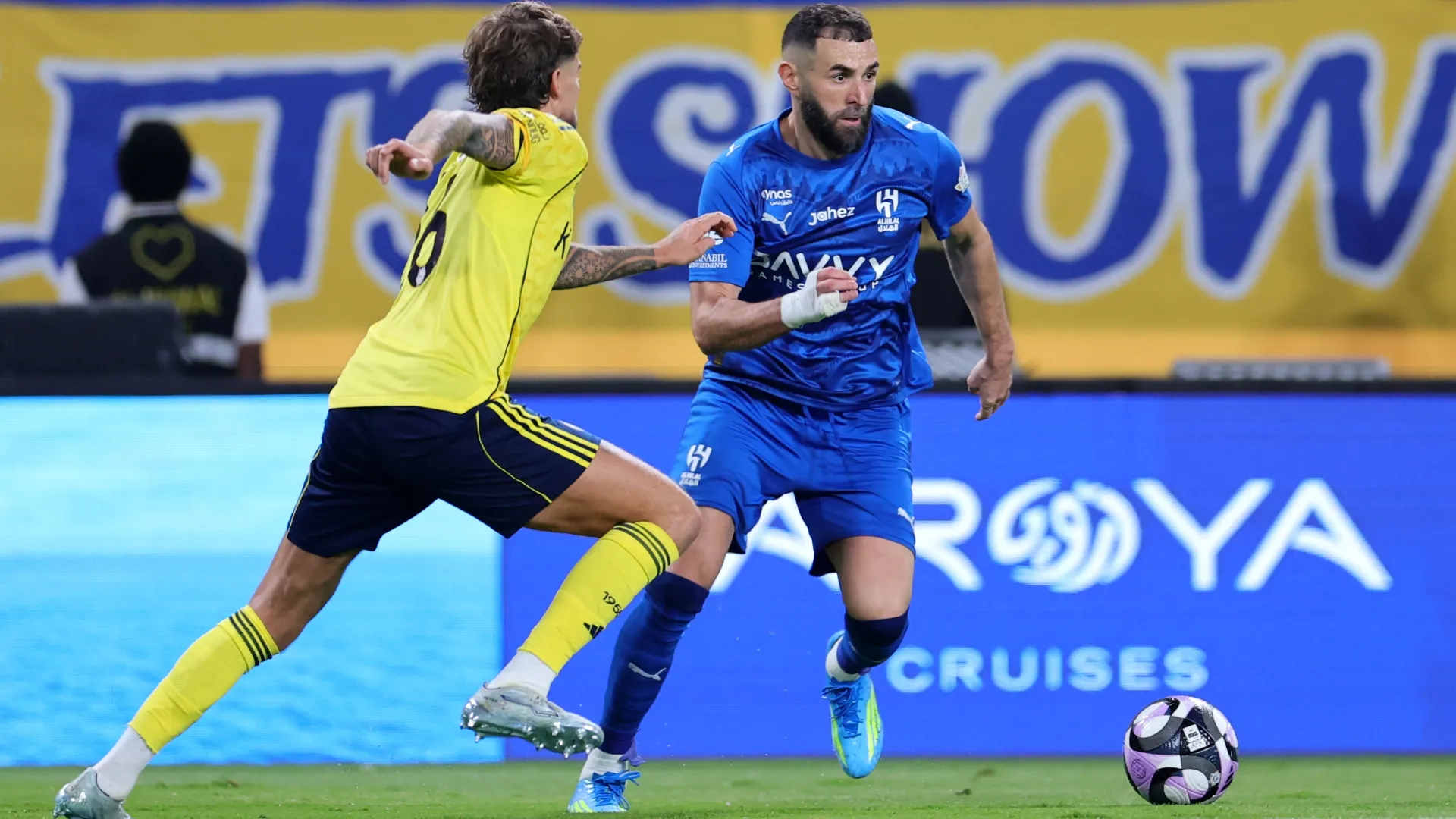Karim Benzema of Al Hilal runs with the ball Lisandro Martinez of Al Nassr.