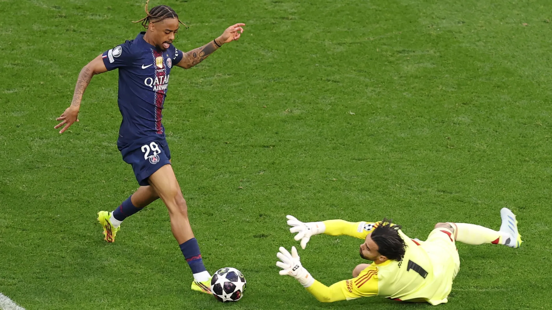 Bradley Barcola of PSG attempts to shoot past David Raya of Arsenal.