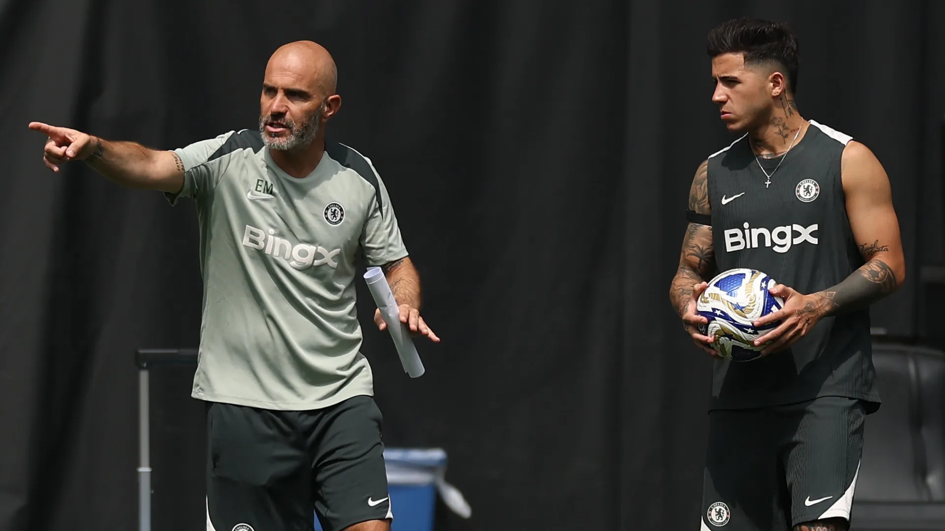 Enzo Fernandez speaks with Enzo Maresca, Head Coach of Chelsea FC, during a training session.