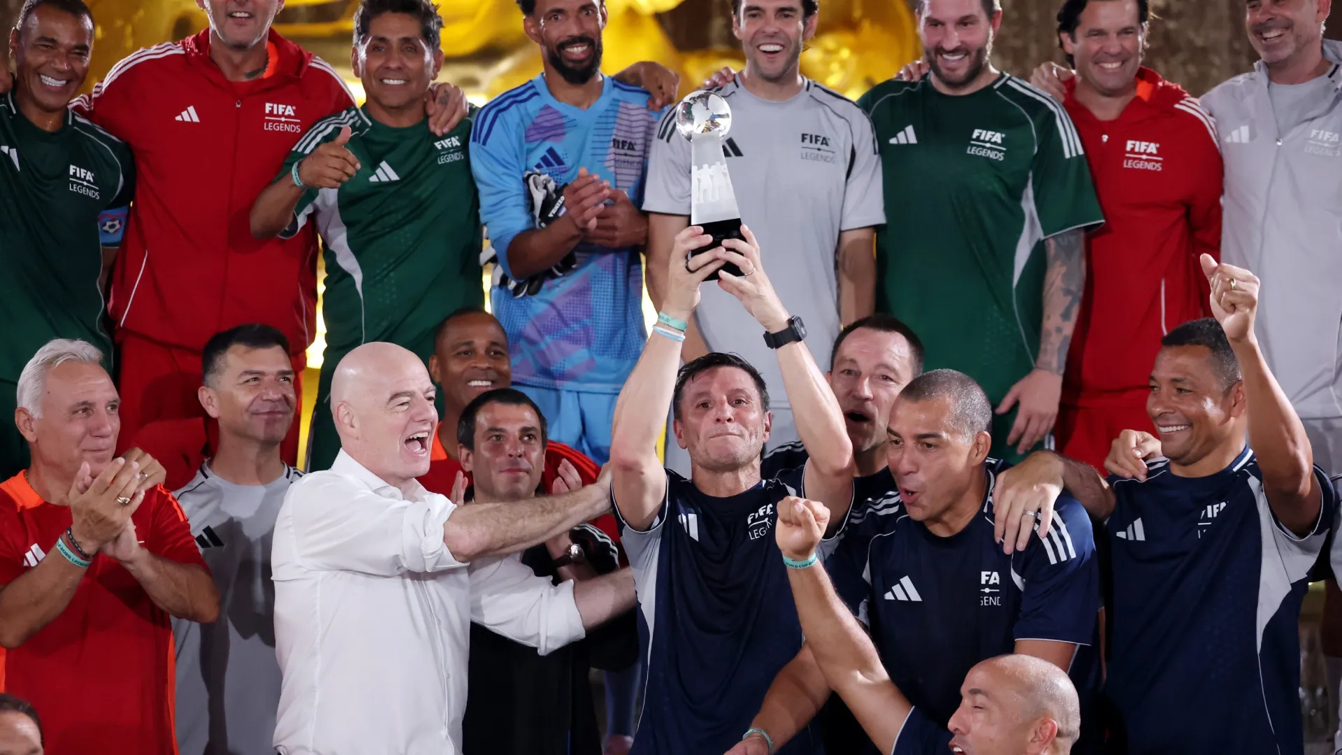 Javier Zanetti of FIFA Legends blue team lifts the trophy alongside FIFA president Gianni Infantino.