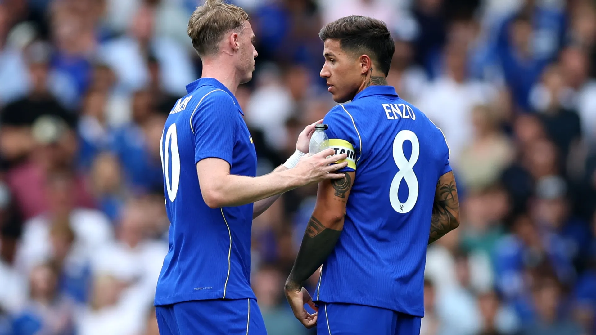 Cole Palmer of Chelsea hands the captain badge to Enzo Fernandez.
